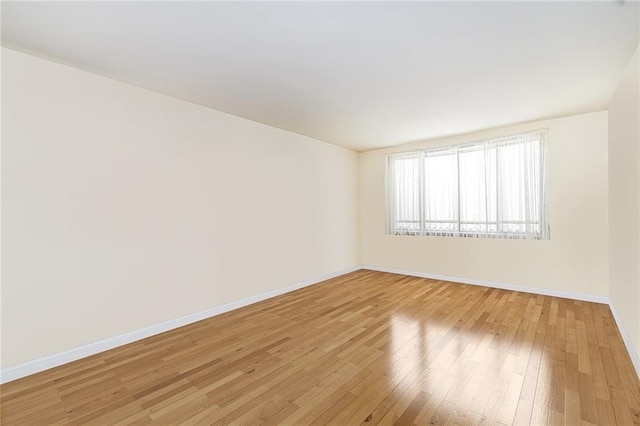 spare room featuring baseboards and light wood-style flooring