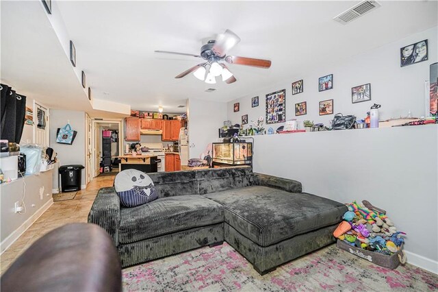 living area with baseboards, ceiling fan, and visible vents