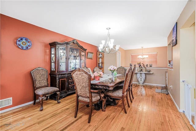 dining room with an inviting chandelier, visible vents, radiator, baseboards, and light wood-style flooring