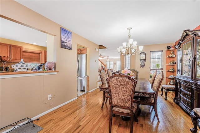 dining space featuring baseboards, light wood finished floors, and a notable chandelier