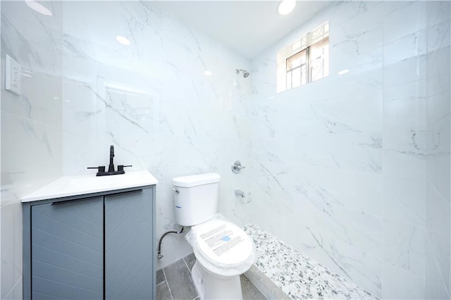 bathroom with tiled shower, toilet, tile walls, and vanity