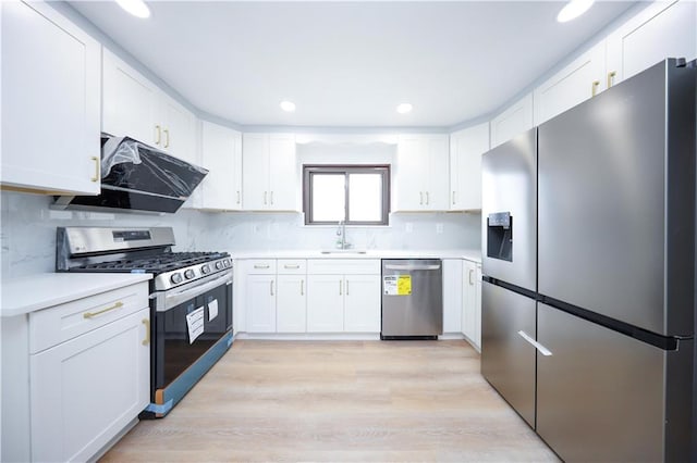 kitchen featuring appliances with stainless steel finishes, a sink, white cabinetry, light wood-style floors, and recessed lighting