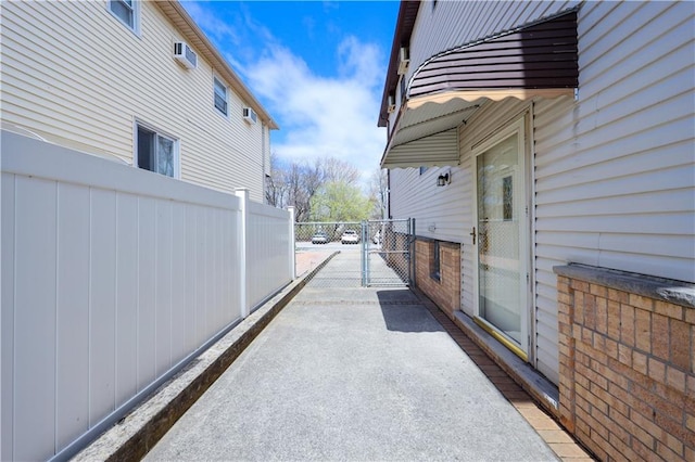 view of side of property with a gate, fence, and an AC wall unit