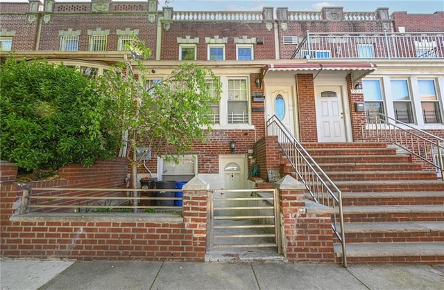 multi unit property featuring brick siding, a fenced front yard, a gate, and entry steps