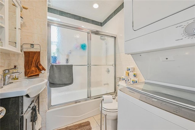 full bathroom featuring vanity, tile patterned flooring, toilet, bath / shower combo with glass door, and stacked washer / drying machine