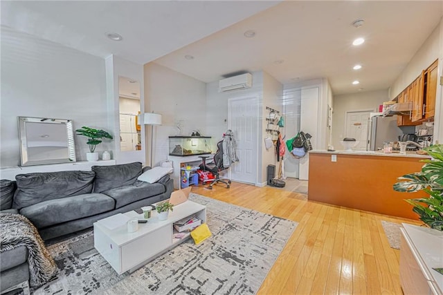 living area featuring an AC wall unit, recessed lighting, and light wood finished floors