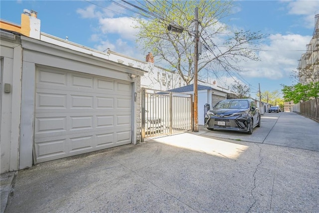 garage featuring fence and concrete driveway