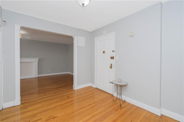 interior space with baseboards, decorative columns, and light wood-style flooring