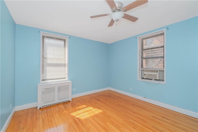 spare room with ceiling fan, baseboards, cooling unit, wood-type flooring, and radiator heating unit