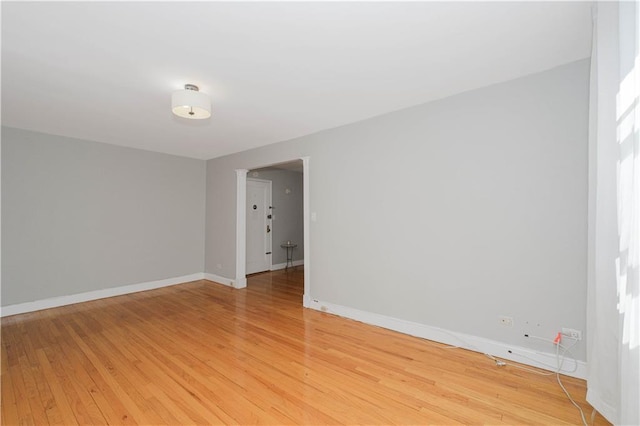 spare room with baseboards and light wood-style floors