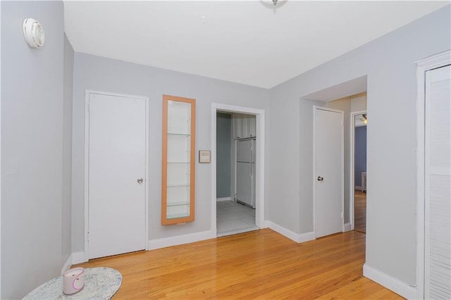 interior space featuring light wood-style floors, baseboards, and white refrigerator
