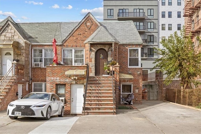townhome / multi-family property with fence, a high end roof, and brick siding