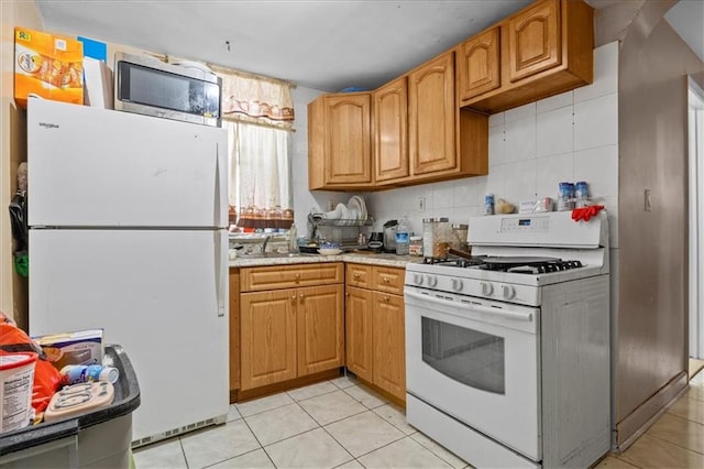 kitchen featuring tasteful backsplash, light countertops, a sink, white appliances, and light tile patterned flooring