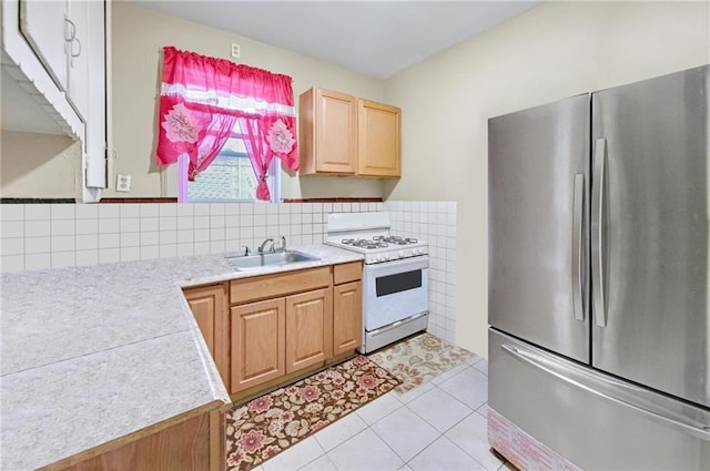 kitchen featuring light brown cabinetry, a sink, light countertops, freestanding refrigerator, and white gas stove