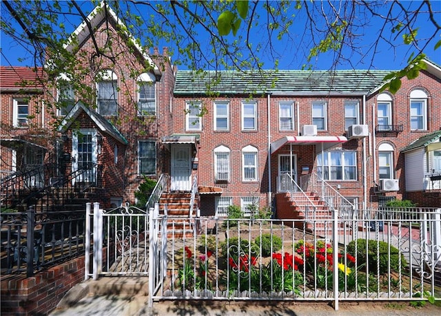 townhome / multi-family property featuring a gate, a fenced front yard, cooling unit, and brick siding