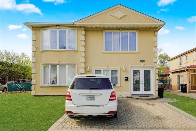view of front of property with french doors, stucco siding, and a front lawn