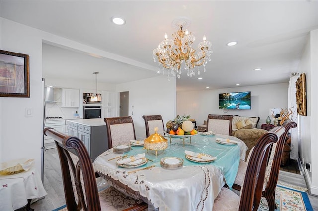 dining space with recessed lighting, light wood-type flooring, and a notable chandelier