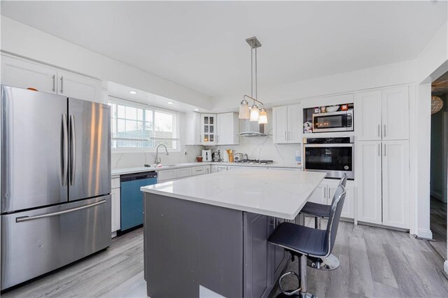 149 Forest St, Staten Island, NY 10314 - kitchen with stainless steel appliances, white cabinetry, light wood-style flooring, a kitchen island, and recessed lighting