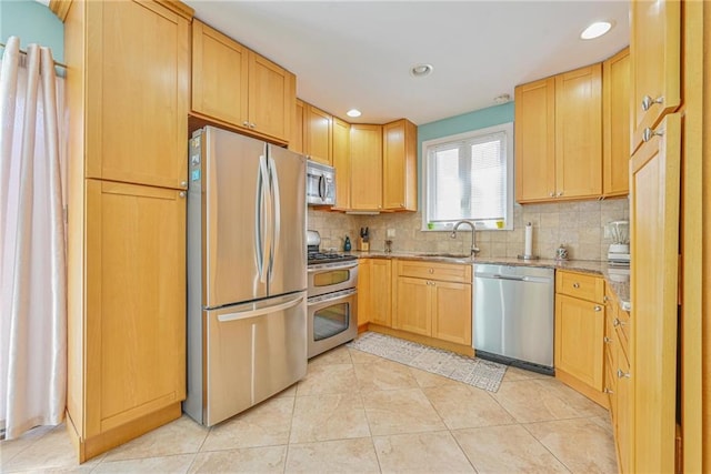 kitchen featuring tasteful backsplash, a sink, light stone counters, stainless steel appliances, and light tile patterned flooring