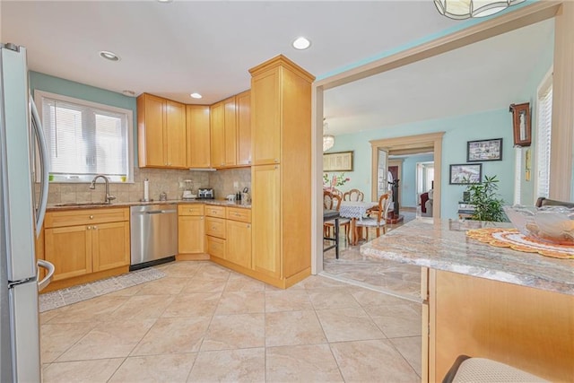 kitchen featuring recessed lighting, light stone counters, a sink, backsplash, and stainless steel appliances