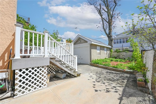 view of patio with fence, stairs, concrete driveway, an outbuilding, and a detached garage