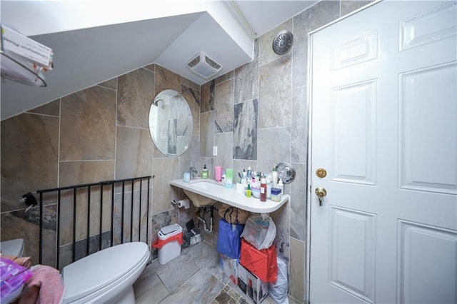bathroom featuring visible vents, toilet, and tile walls