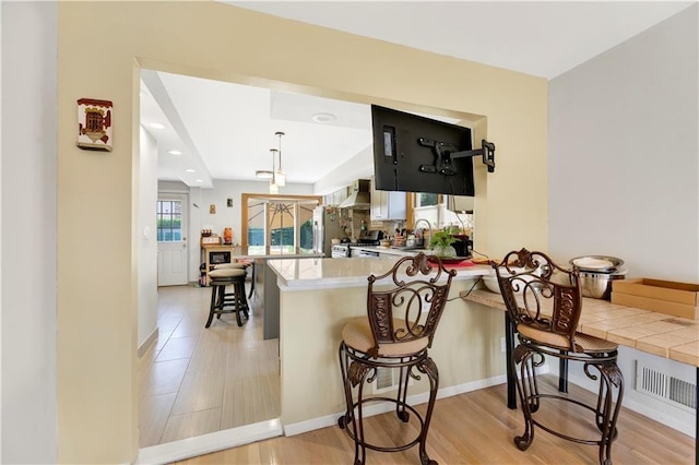 30 Beverly Rd, Staten Island, NY 10305 - kitchen featuring a peninsula, wall chimney range hood, a breakfast bar area, stainless steel range oven, and recessed lighting