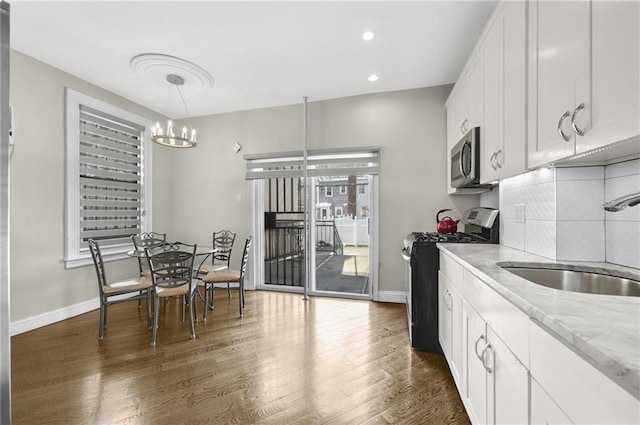kitchen featuring white cabinets, an inviting chandelier, a sink, stainless steel appliances, and dark wood-style floors
