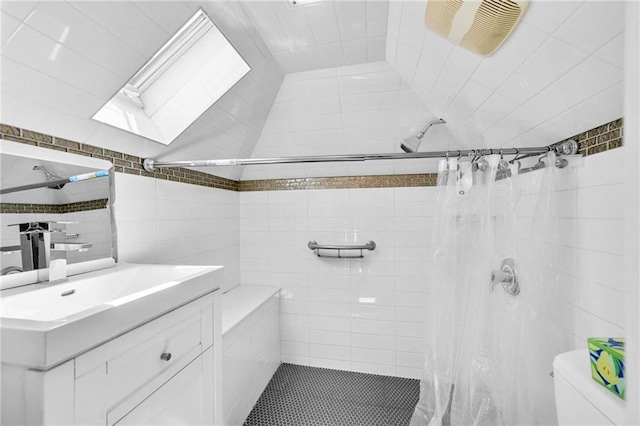 bathroom featuring toilet, tile walls, a tile shower, and vanity