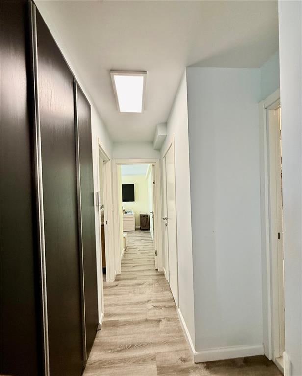 hall with light wood-style floors and baseboards