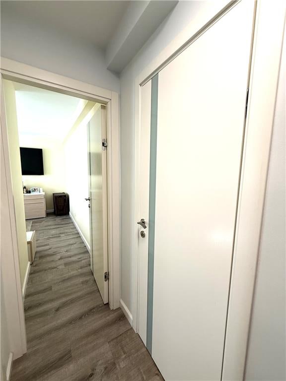 corridor featuring baseboards and wood finished floors