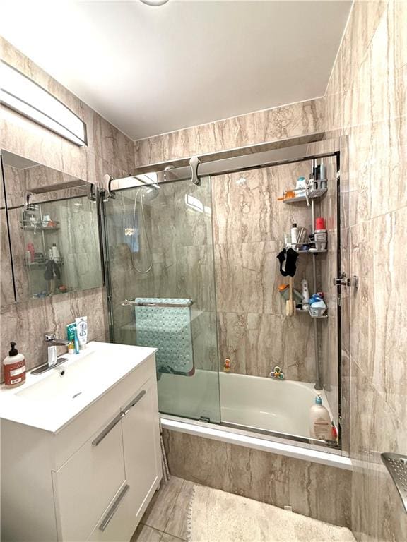 full bathroom featuring tiled shower / bath combo, tile walls, and vanity