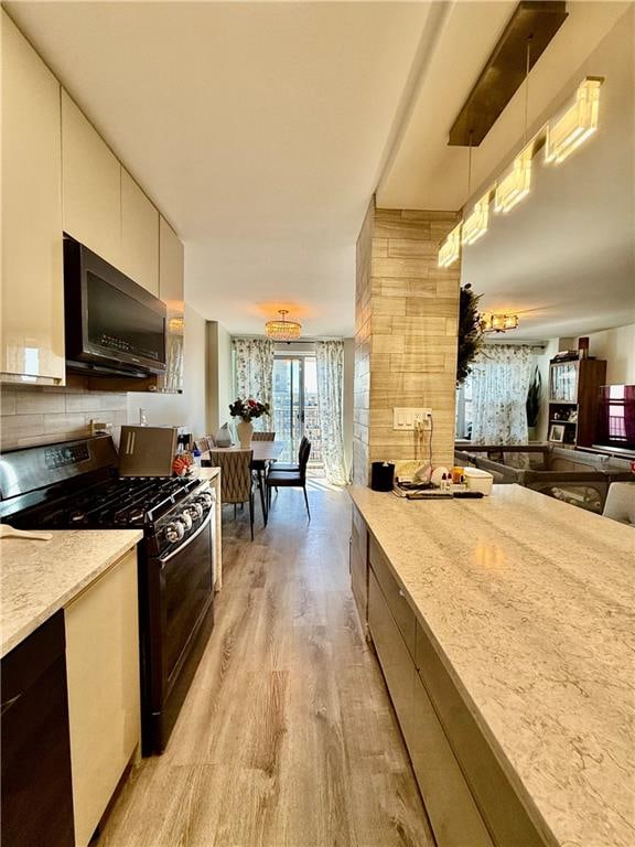 kitchen featuring decorative backsplash, modern cabinets, white cabinets, light wood finished floors, and gas stove