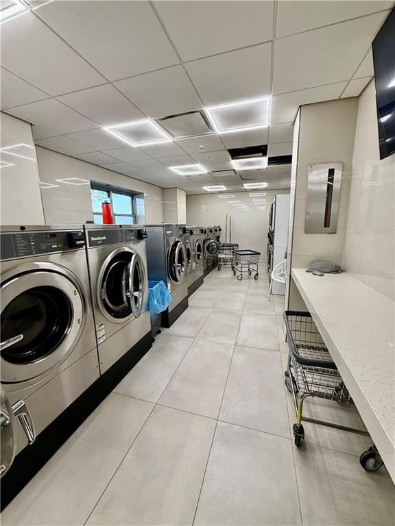 common laundry area featuring washing machine and clothes dryer and light tile patterned flooring