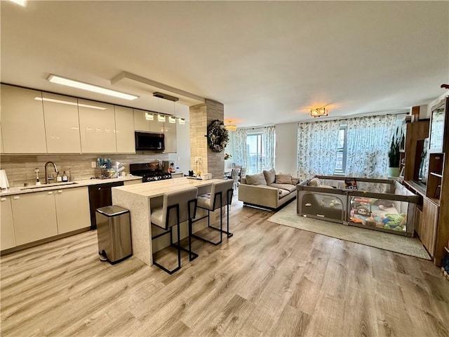 kitchen with backsplash, appliances with stainless steel finishes, modern cabinets, a sink, and open floor plan