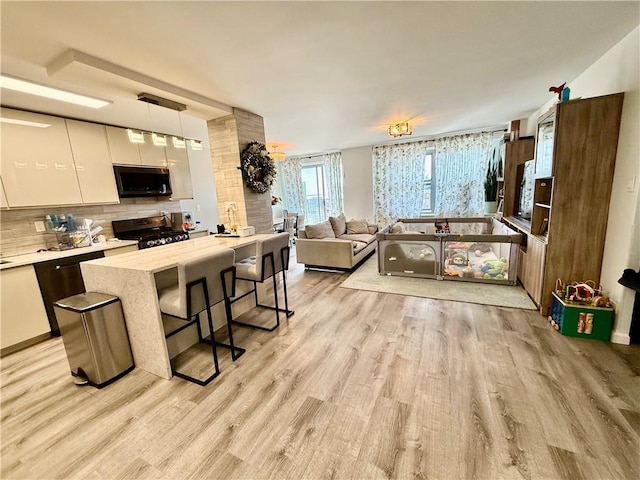 kitchen featuring modern cabinets, light wood-type flooring, white cabinetry, appliances with stainless steel finishes, and backsplash