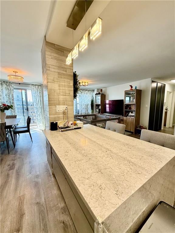 kitchen with a peninsula, decorative light fixtures, and wood finished floors