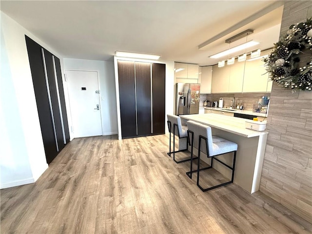 kitchen featuring stainless steel fridge, modern cabinets, a breakfast bar, and light wood-type flooring