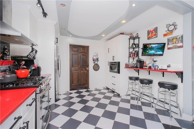 kitchen featuring white cabinetry, stainless steel appliances, wall chimney exhaust hood, and dark floors