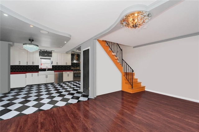 kitchen with stainless steel appliances, tasteful backsplash, wood finished floors, wall chimney exhaust hood, and white cabinetry