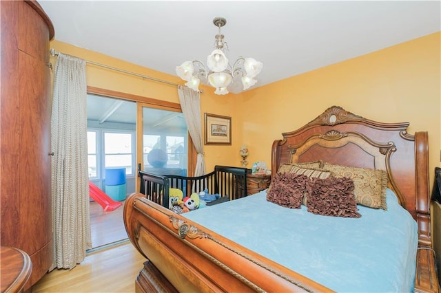 bedroom featuring a notable chandelier, light wood finished floors, and access to outside