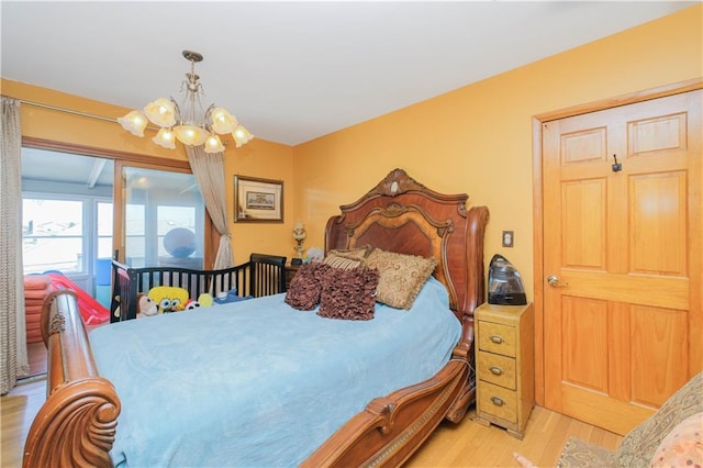 bedroom with a notable chandelier, access to outside, and light wood-style flooring