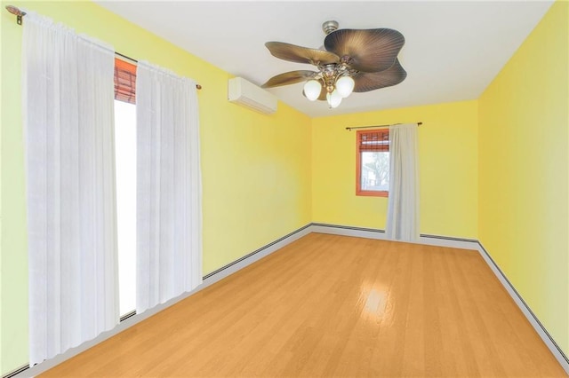 spare room with a ceiling fan, a baseboard radiator, a wall mounted air conditioner, baseboards, and wood finished floors
