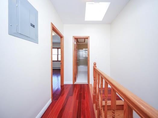 299 Bay 13th St, Brooklyn, NY 11214 - hall with electric panel, a skylight, wood finished floors, a baseboard radiator, and an upstairs landing