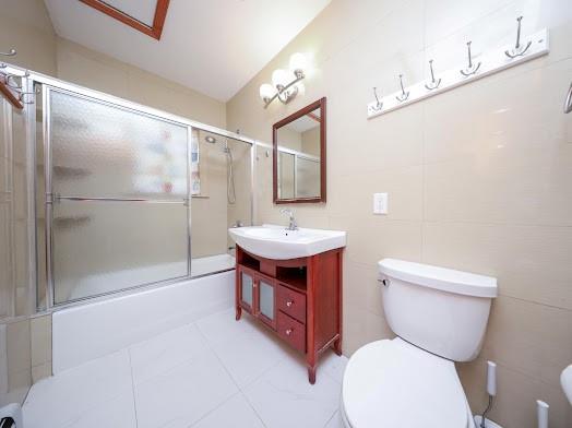 299 Bay 13th St, Brooklyn, NY 11214 - bathroom with toilet, vanity, bath / shower combo with glass door, and tile patterned floors