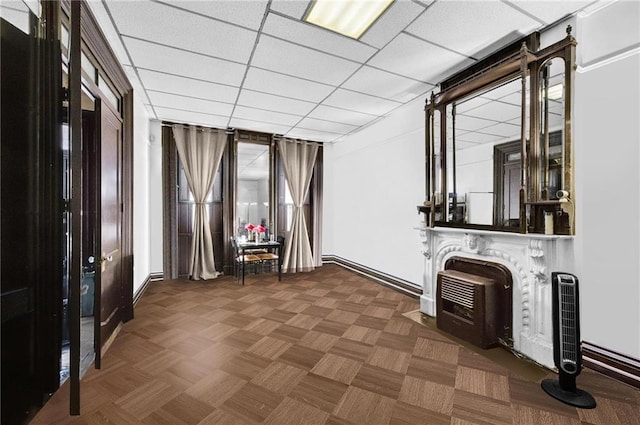 unfurnished living room featuring baseboards and a drop ceiling