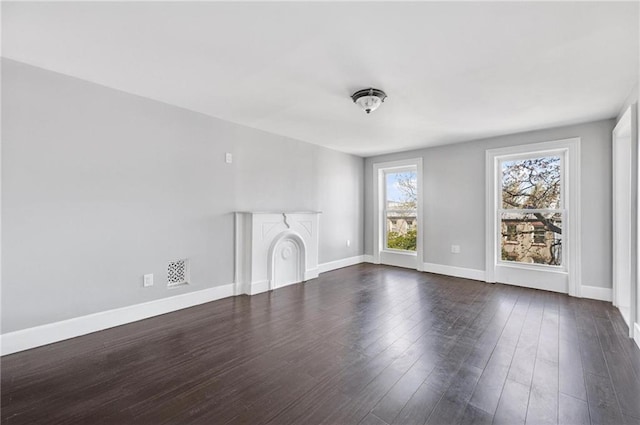 unfurnished living room featuring baseboards, visible vents, and dark wood finished floors