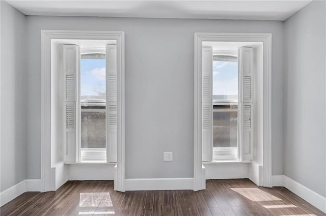 spare room with baseboards and dark wood-style floors