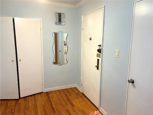 hallway with crown molding, wood finished floors, and baseboards