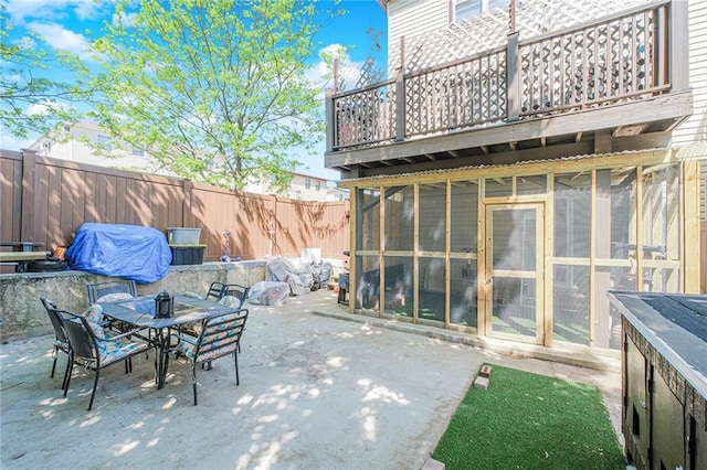 view of patio featuring outdoor dining area, a fenced backyard, exterior structure, and a balcony